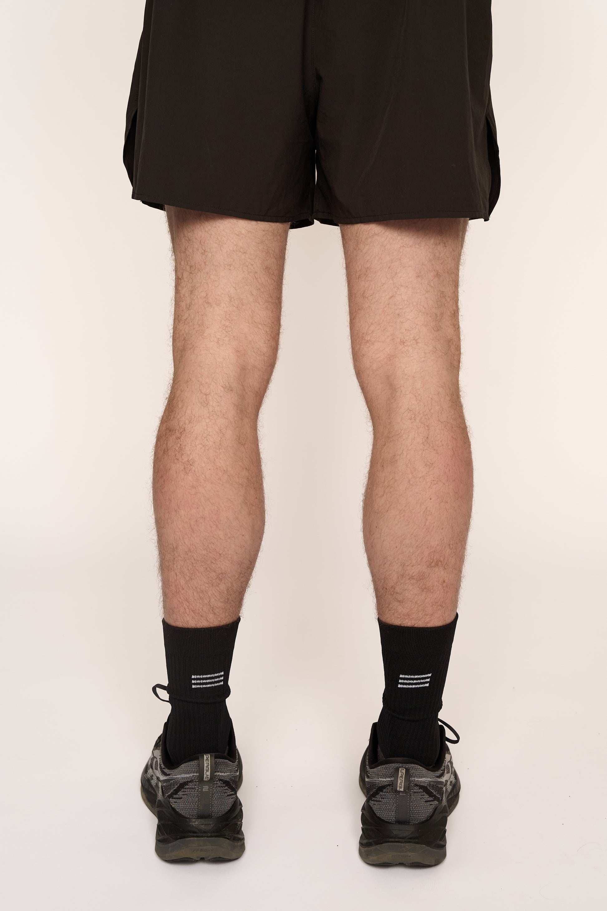 THE DELIVERY SOCKS - BLACK, featuring a sleek design, worn with shorts and athletic shoes.