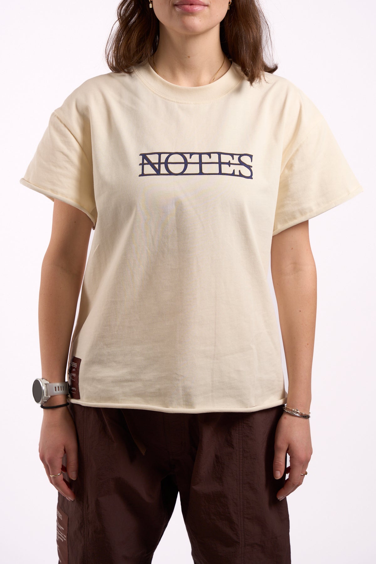 Anniversary Tee in off white, front close-up showing Notes logo