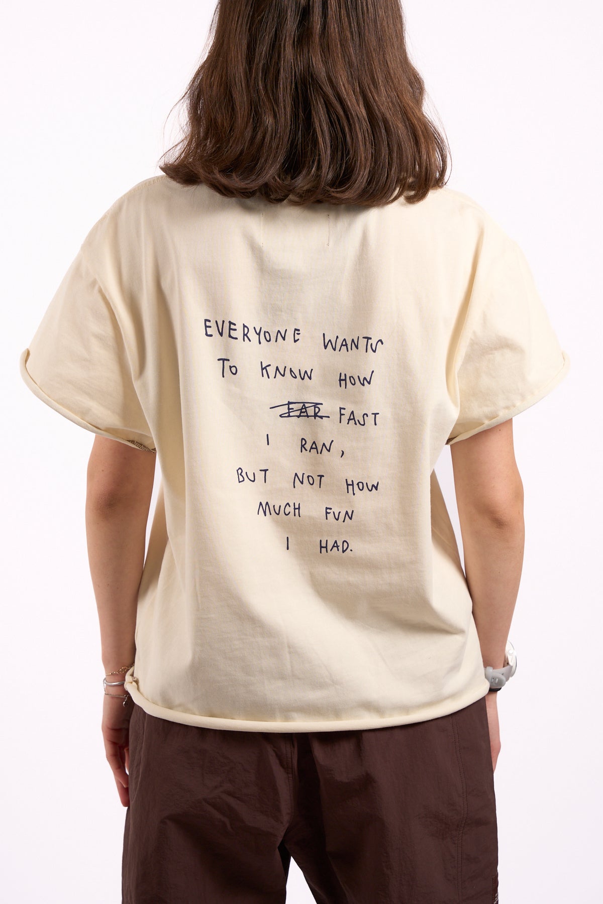 Anniversary Tee in off white, back print close-up reading "Everyone wants to know how fast I ran, but not how much fun I had"