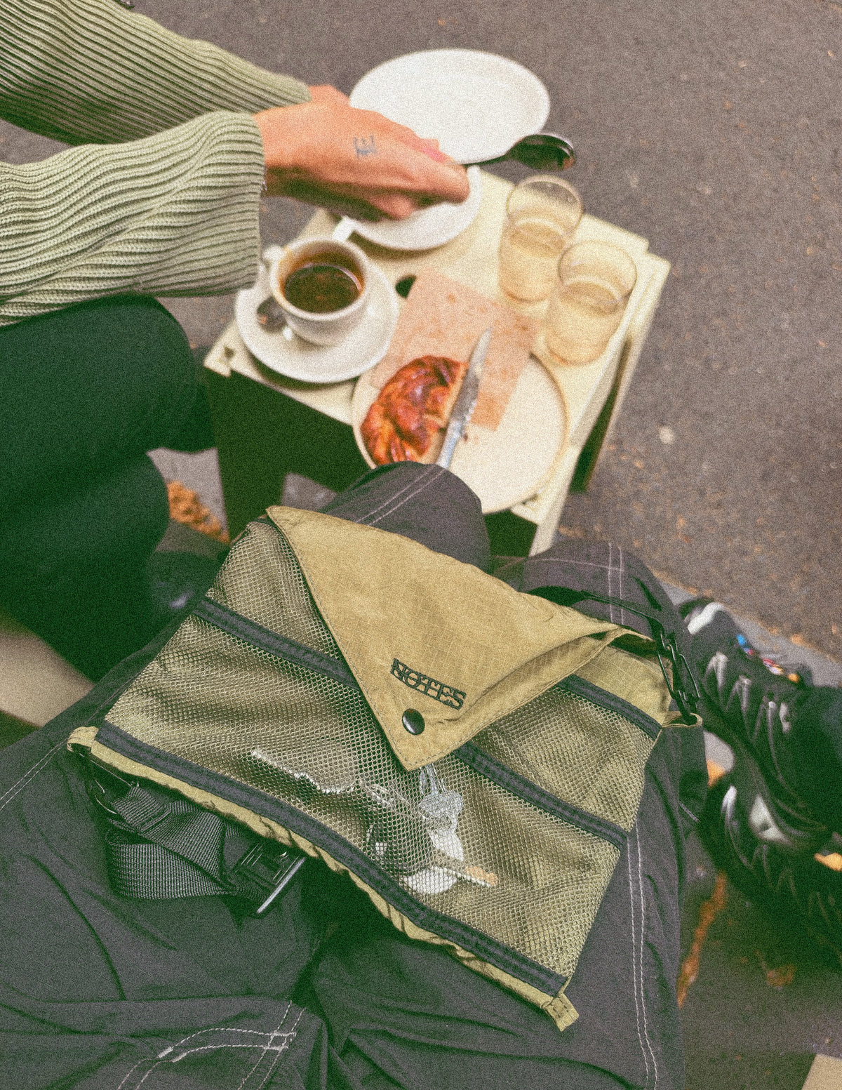Musette Messenger Running Bag in Olive/Black, lying open beside a cafe table