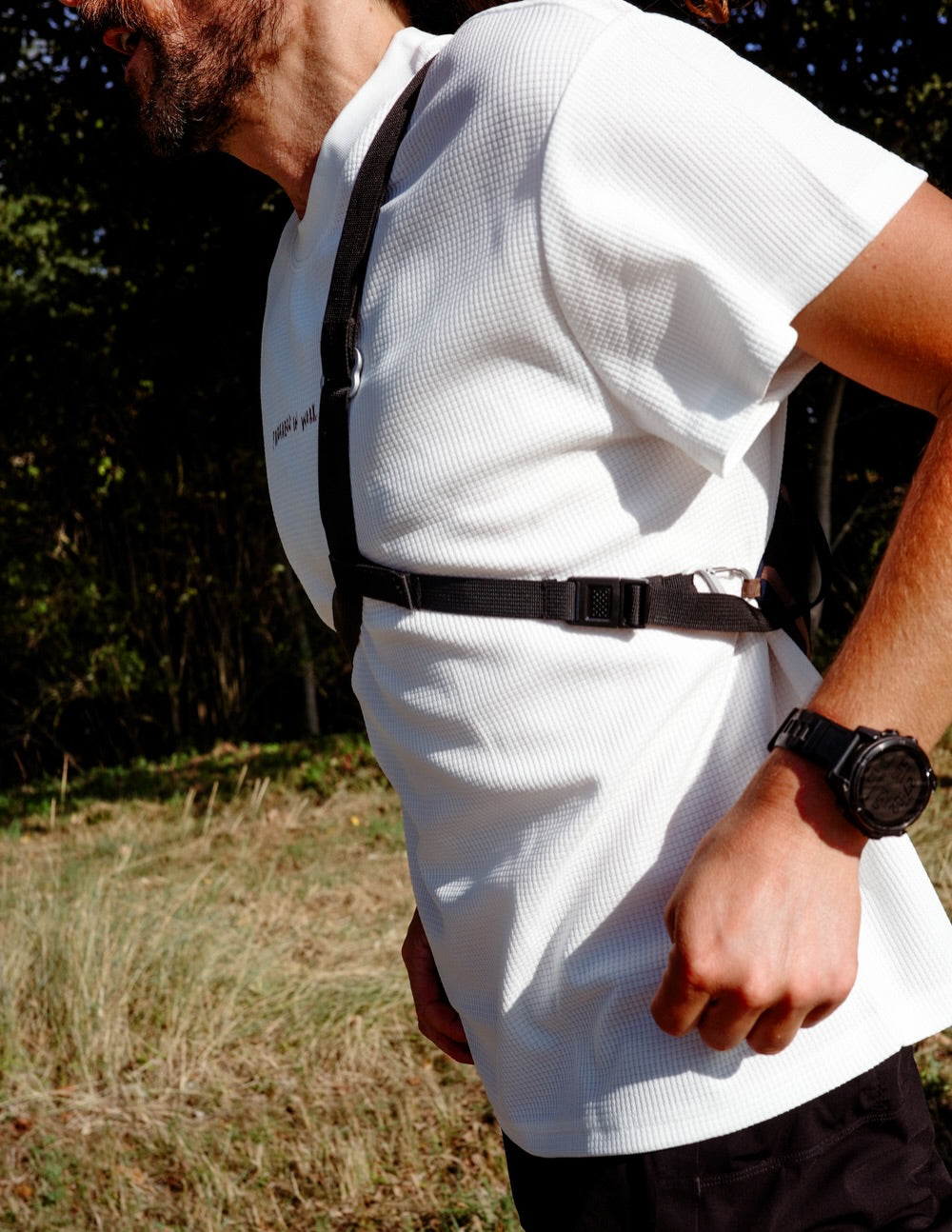 Runner wearing the Musette Messenger Running Bag in Olive/Black, strap across a white tee, side view