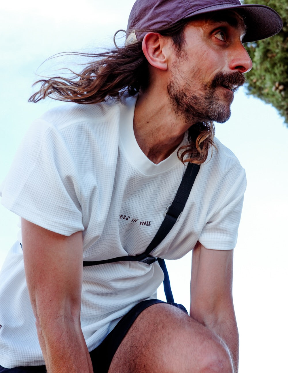 Runner wearing the Musette Messenger Running Bag strap over a white tee, close up